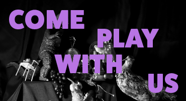 Black and white photograph of a still-life setup of various objects such as toy dinosaur, disco ball, barbie, a wombat and a sloth. Text Come Play with Us floats across the top of the image in a bright purple 