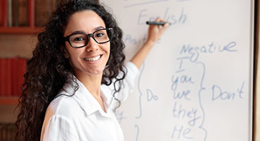 Woman with glasses writing on whiteboard and smiling
