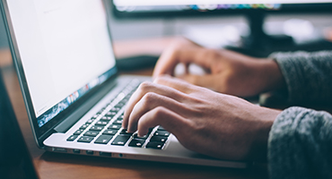 Close-up of hands typing on a laptop