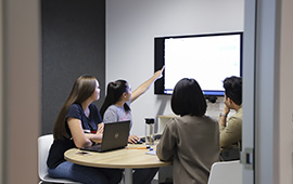 Four students in group study room using a shared screen