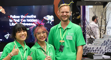 Student staff in green shirts grinning and smiling at camera