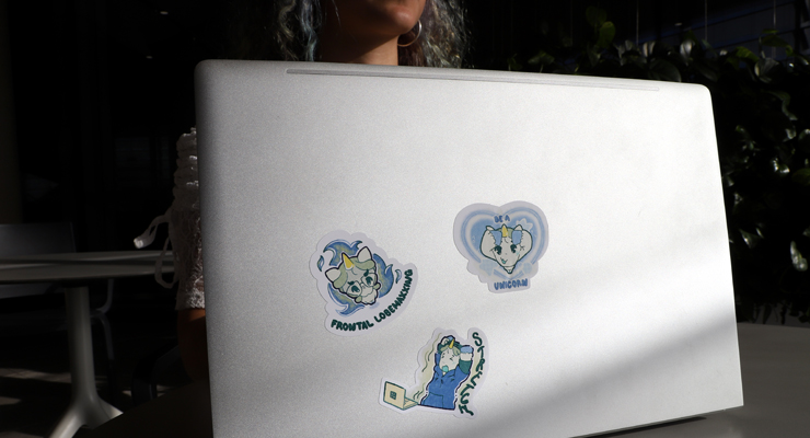 Laptop sitting in sun with 3 unicorn stickers on it