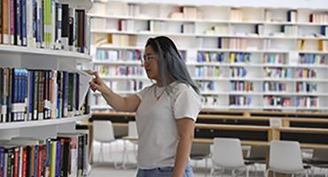 Girl browsing book shelves in library