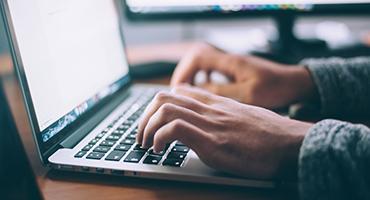 Close-up of hands typing on a laptop