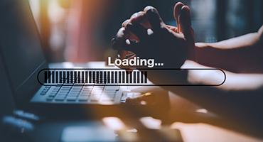 Hands at laptop with a loading symbol super imposed