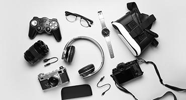 Flat lay of tech gadgets, controllers, camera, headphones, VR headset, cords
