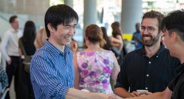 3 students shaking hands and networking at an event