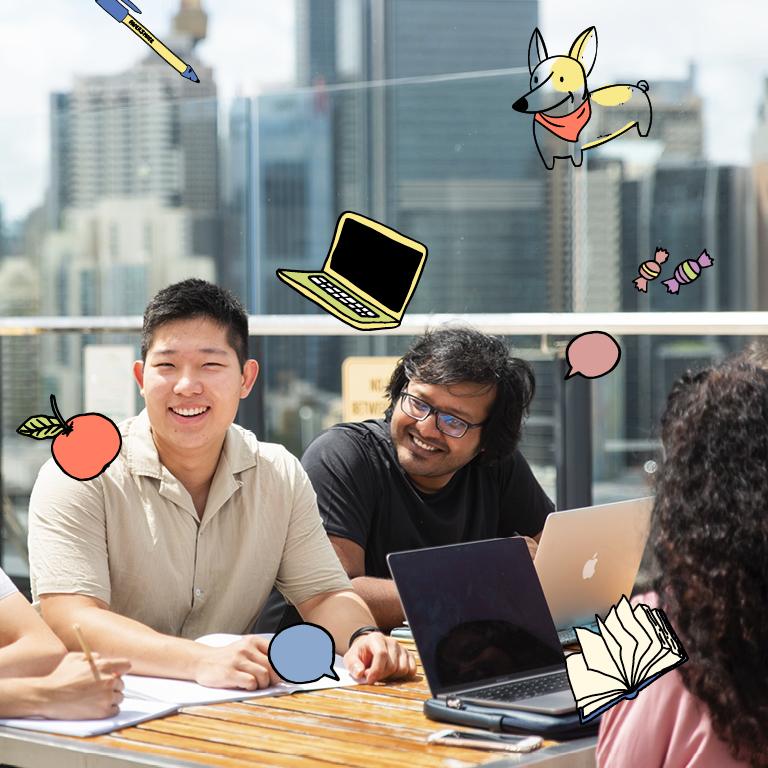 Smiling students working together at table with laptops