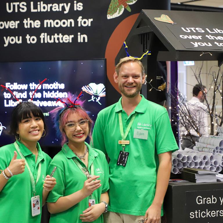 Student Guides in distinctive green uniforms standing and smiling in front of Learning Hub