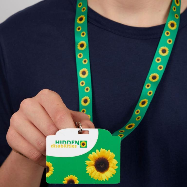 Person holding the Hidden Disabilities Sunflower initiative lanyard (green lanyard with yellow sunflowers)