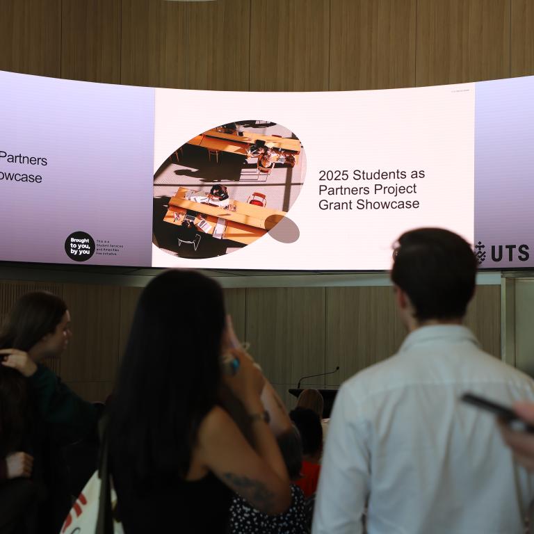 Students in front of illuminated screen that reads 2025 Students as Partners Project Grant Showcase