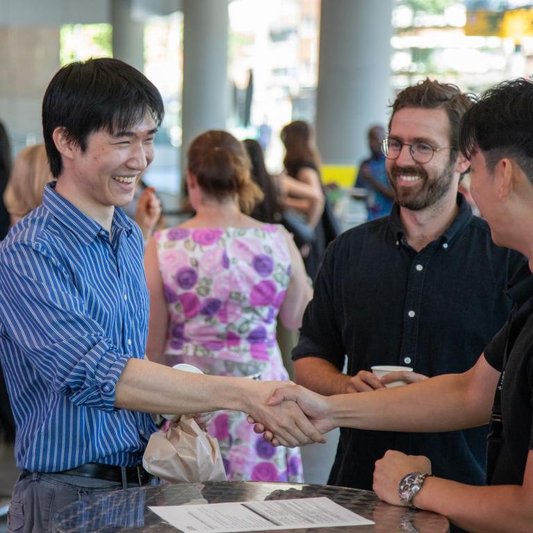 3 students shaking hands and networking at an event