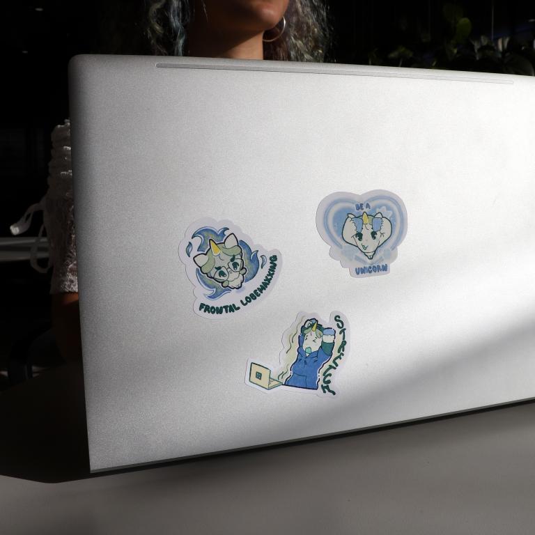 Laptop sitting in sun with 3 unicorn stickers on it