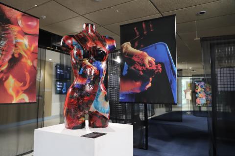 Photo of exhibition- Sculpture on a plinth with hanging photos 