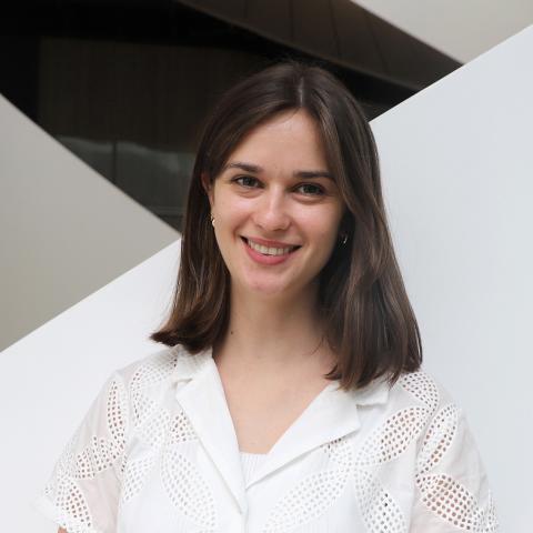 Tess in a white shirt standing against a white staircase