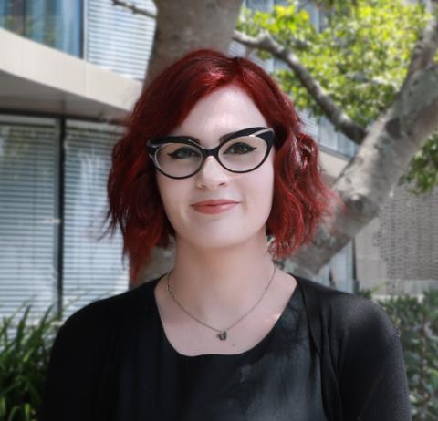 Photograph of Alex McManus taken against a backdrop of trees and a glass building