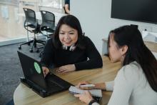 Two women sitting down and looking at a laptop