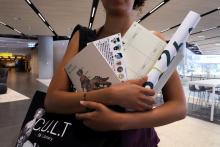 Person holding planners, notebooks, tote bag and stickers in their arms