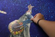 Hand positioning cut collage pieces on a blue background
